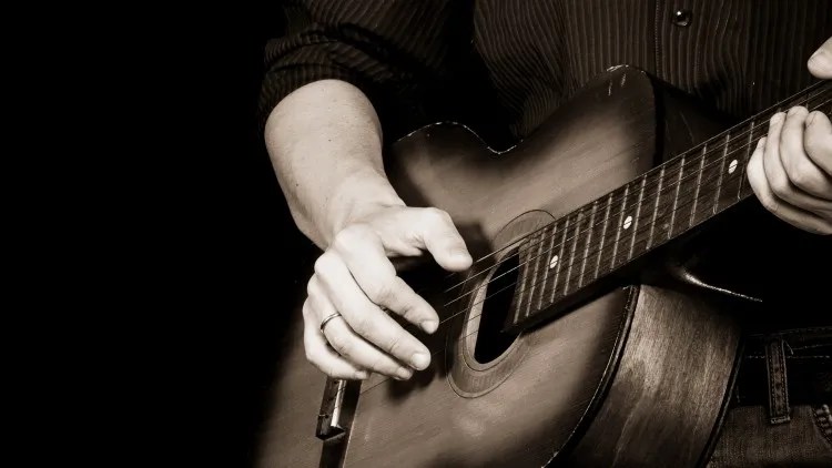 black and white photograph showing close up of hands playing blues guitar