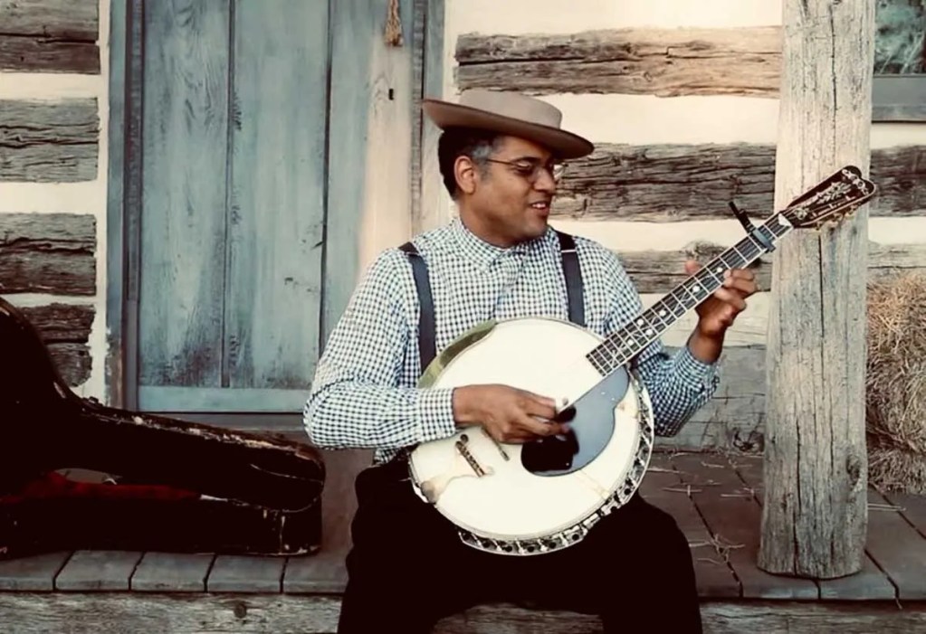 Dom-Flemons-plays-his-1920s Clef Club Deluxe guitar banjo