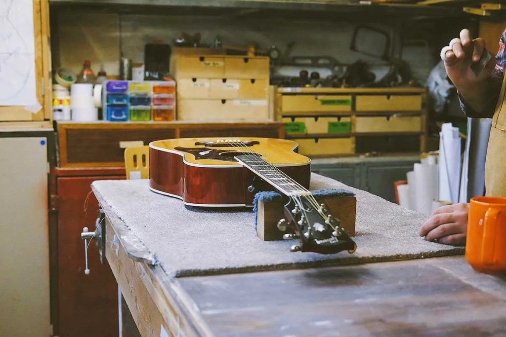 An acoustic guitar rests on a workbench. Photo: Jonny swales
